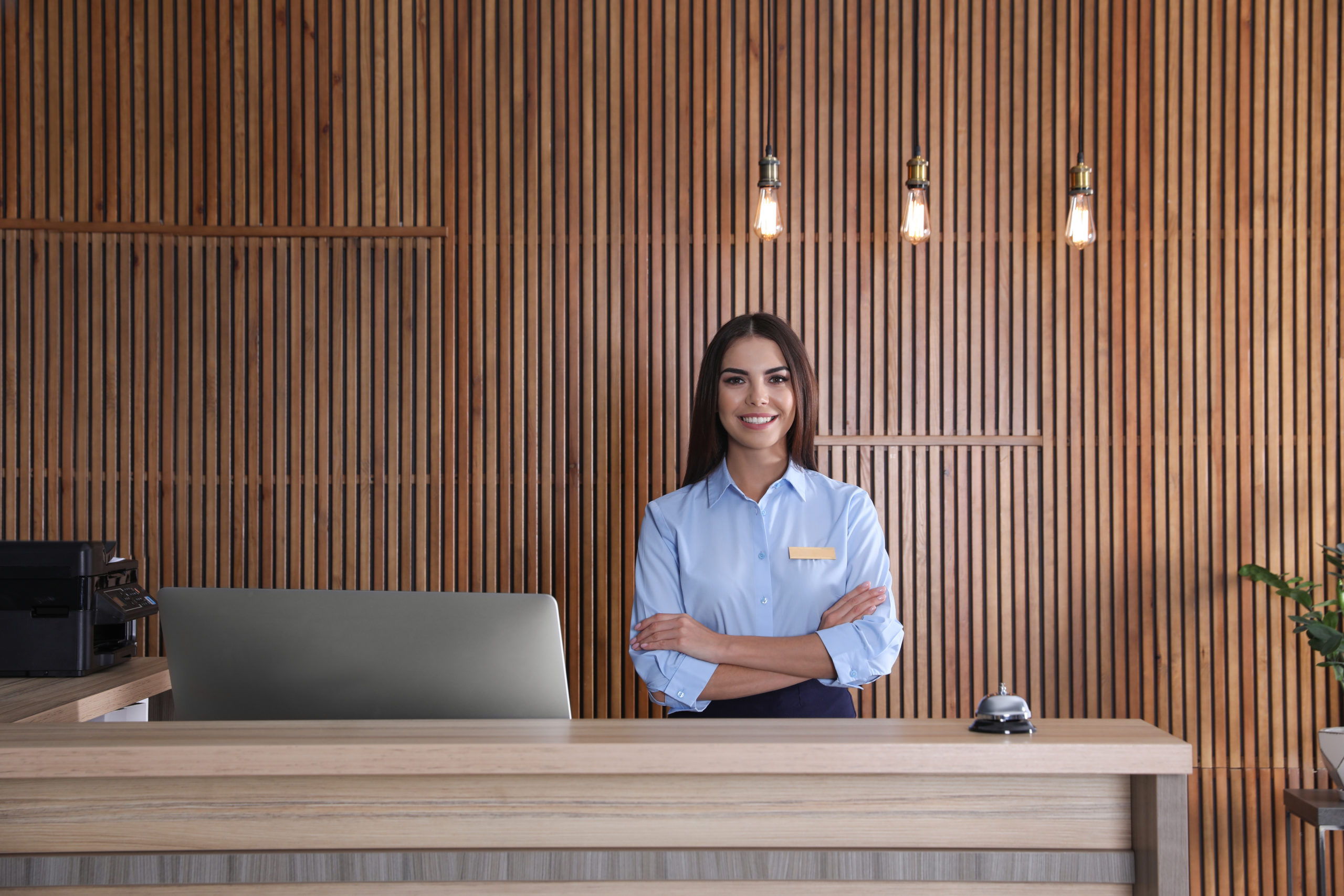 commercial-and-hospitality-Design-by-MDfx-woman-stading-at-hotel-reception-beautifully-designed-with-wooden-panel-