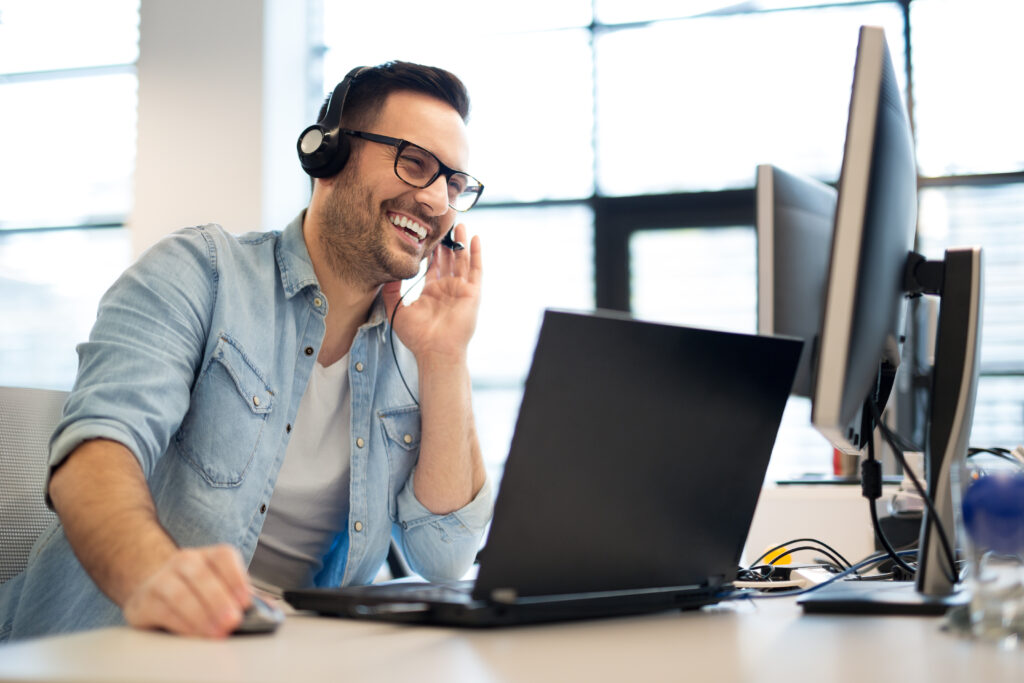 Young smiling male call center operator doing his job with a headset.Portrait of call center worker at office.