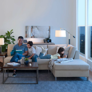 A family relaxing in a living room with a Lutron blind at the window.